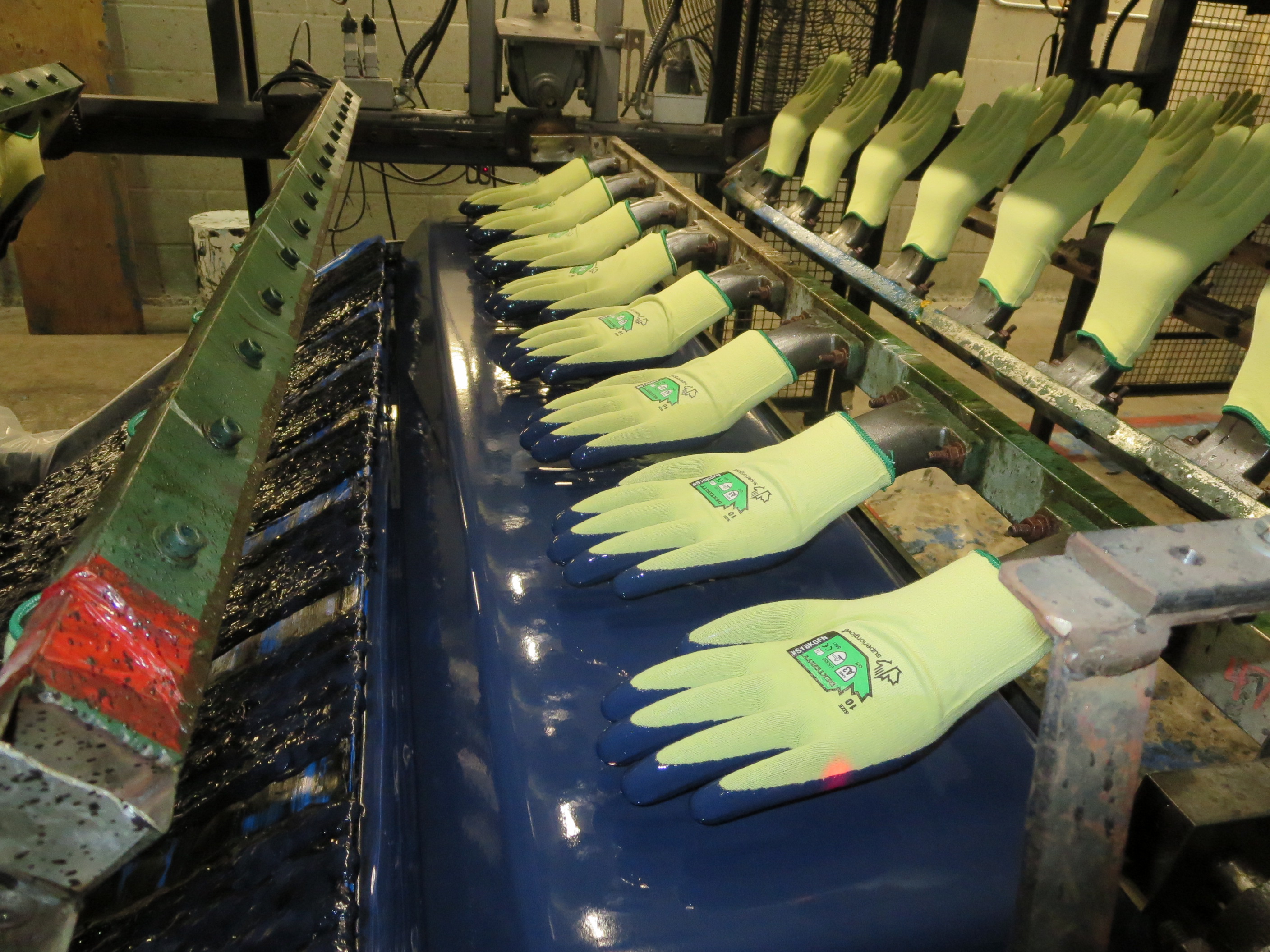 Superior Glove kevlar gloves being dipped in blue nitrile palm dip coating