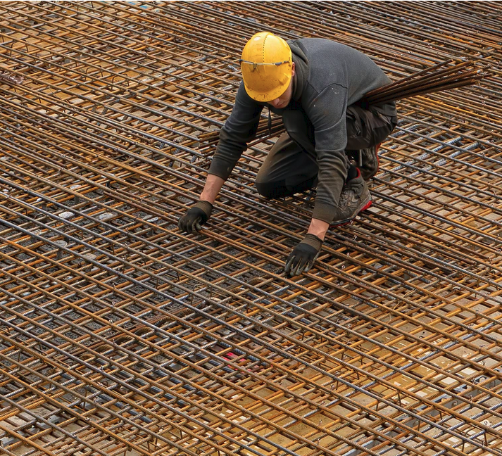 Worker kneeling on top of a steel rebar grid