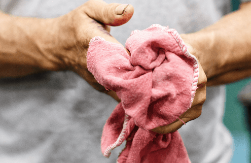 Worker wiping hands with disposable red shop cloths 