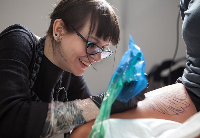 Tattooist stencling an arm with gloves and infection barrier for tattoo machine